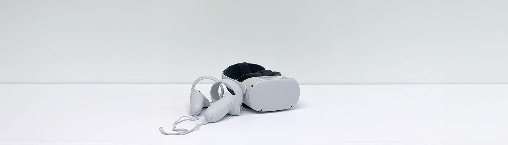 A standalone VR headset lying on a grey table. Two standart controllers lying next to it.